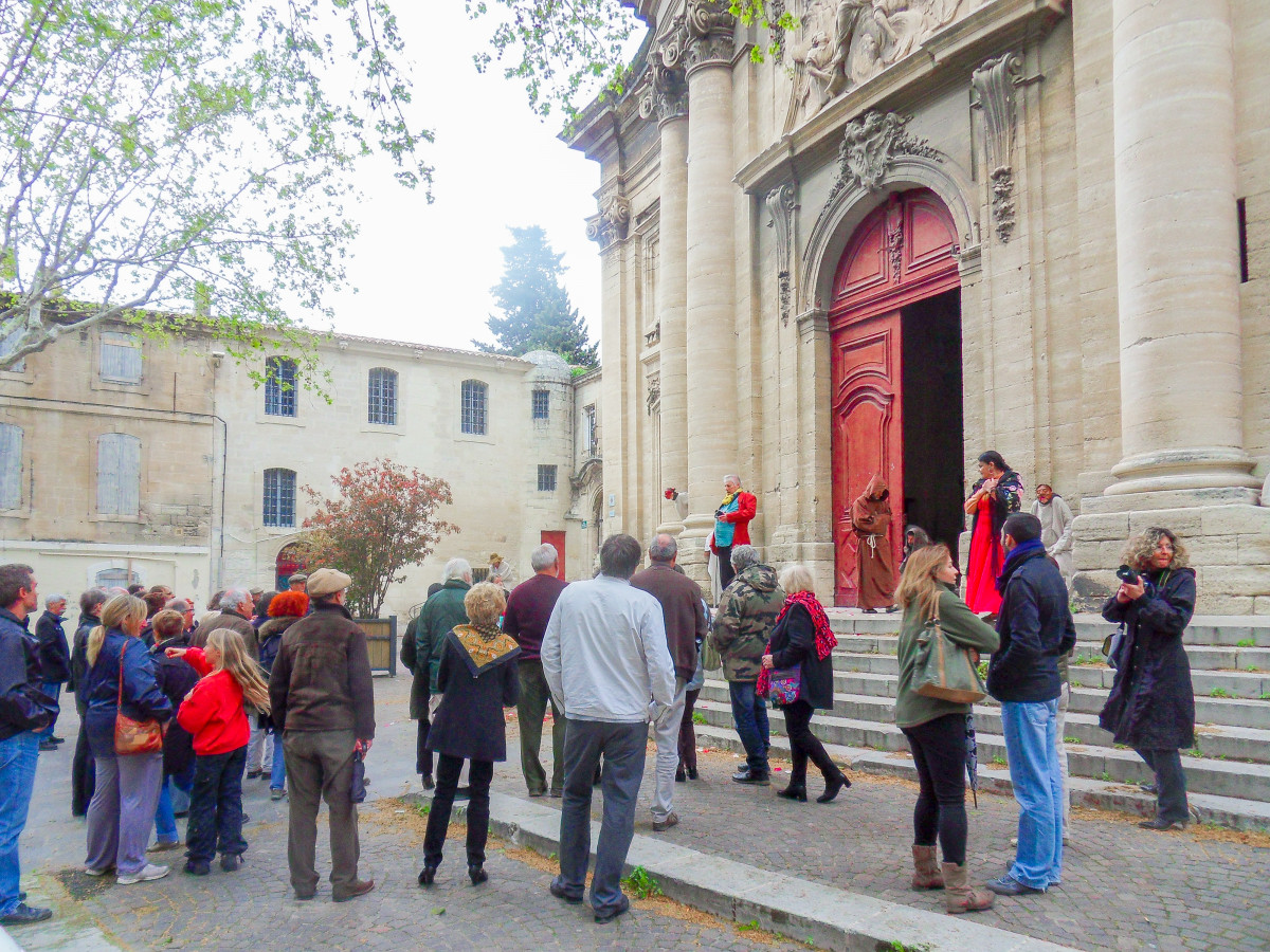 Group of visitors on a guided tour outside the entrance to Notre-Dame-des-Pommiers Collegiate Church in Beaucaire