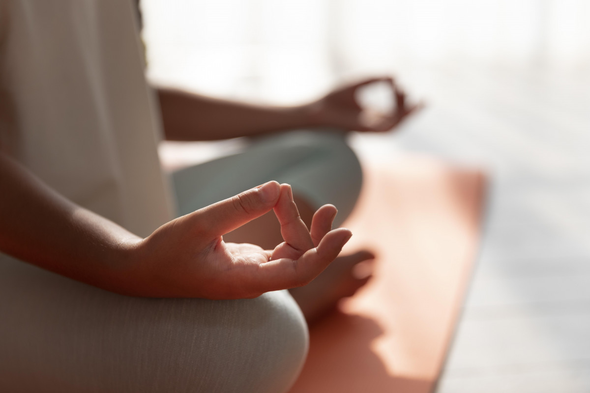 Close-up of a person seated in meditation on a yoga mat, with their hands forming a mudra, illustrating yoga and tasting sessions at Domaine Pierre-Feu in Jonquières-Saint-Vincent.