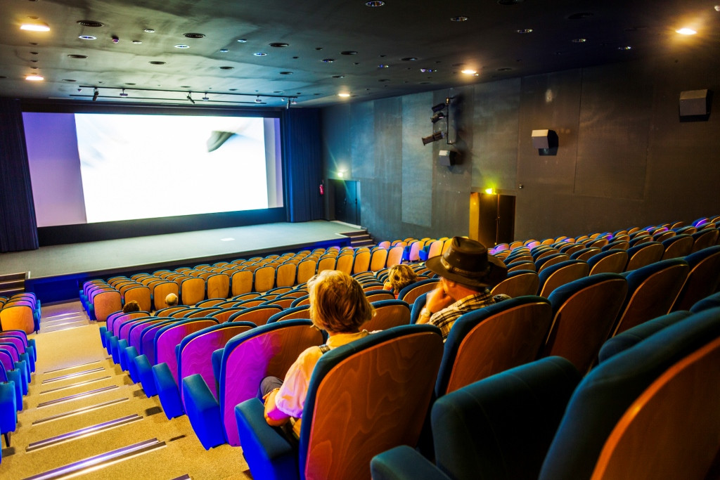 Wide view of the Pont du Gard cinema auditorium, showing the large projection screen, rows of colourful seats and visitors watching.