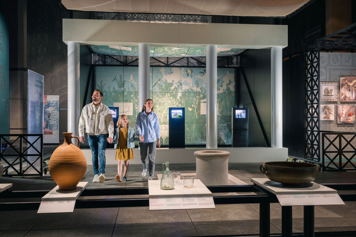 Visitors exploring an exhibition gallery at the Pont du Gard Museum, with objects displayed on stands and museum interpretation exhibits.