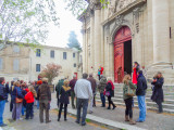Group of visitors on a guided tour outside the entrance to Notre-Dame-des-Pommiers Collegiate Church in Beaucaire