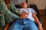 Close-up of a Luma Shiatsu practitioner's hands applying gentle pressure to the abdomen of a person lying on a treatment table in Bellegarde.
