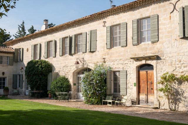Domaine des Clos – Stone Building and Garden Stone façade of Domaine des Clos with shuttered windows, wooden doors, climbing plants and a lawn in the foreground.